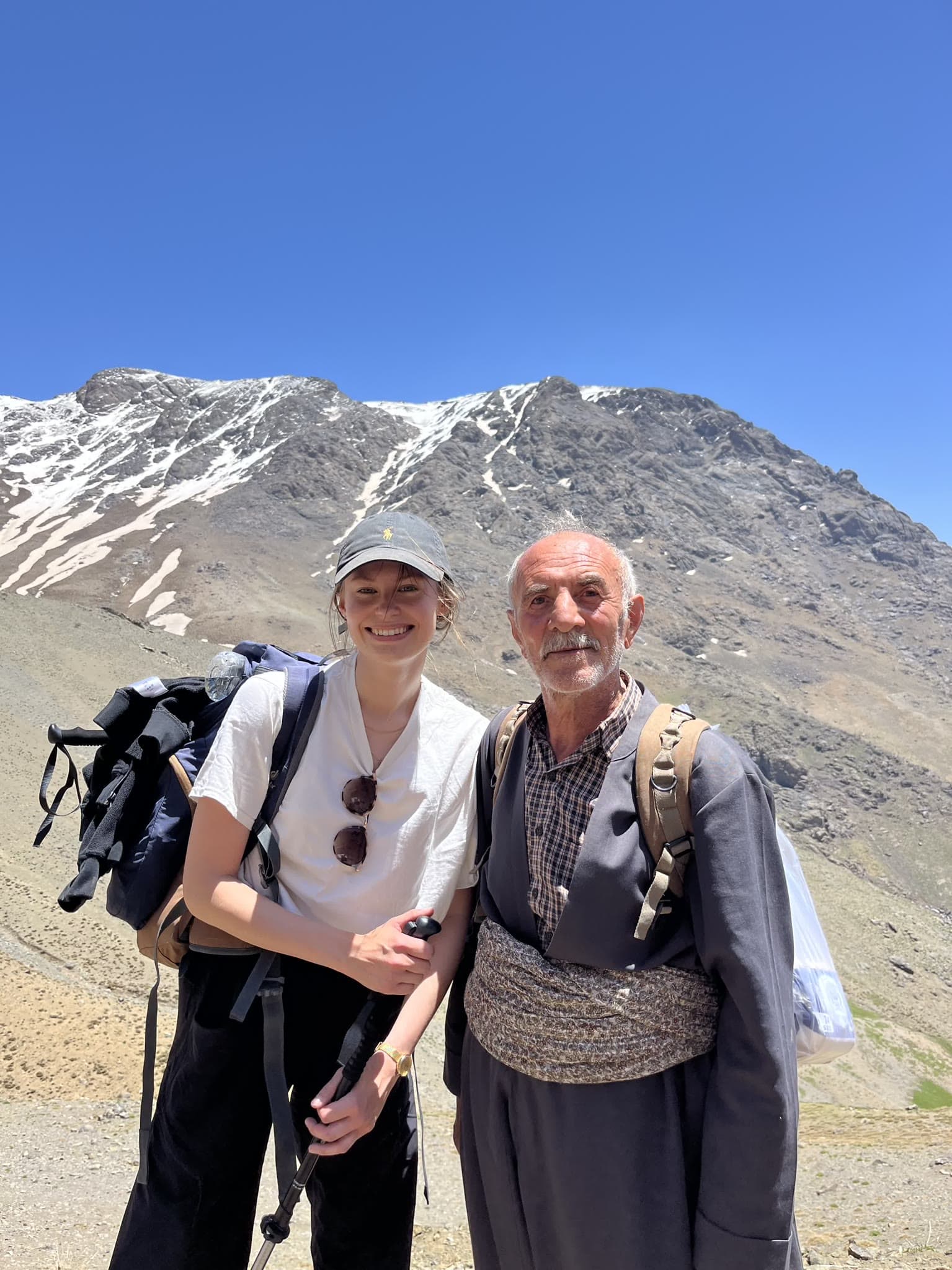 Teilnehmerin mit lokalem Guide in traditioneller Kleidung vor dem Halgurd-Massiv