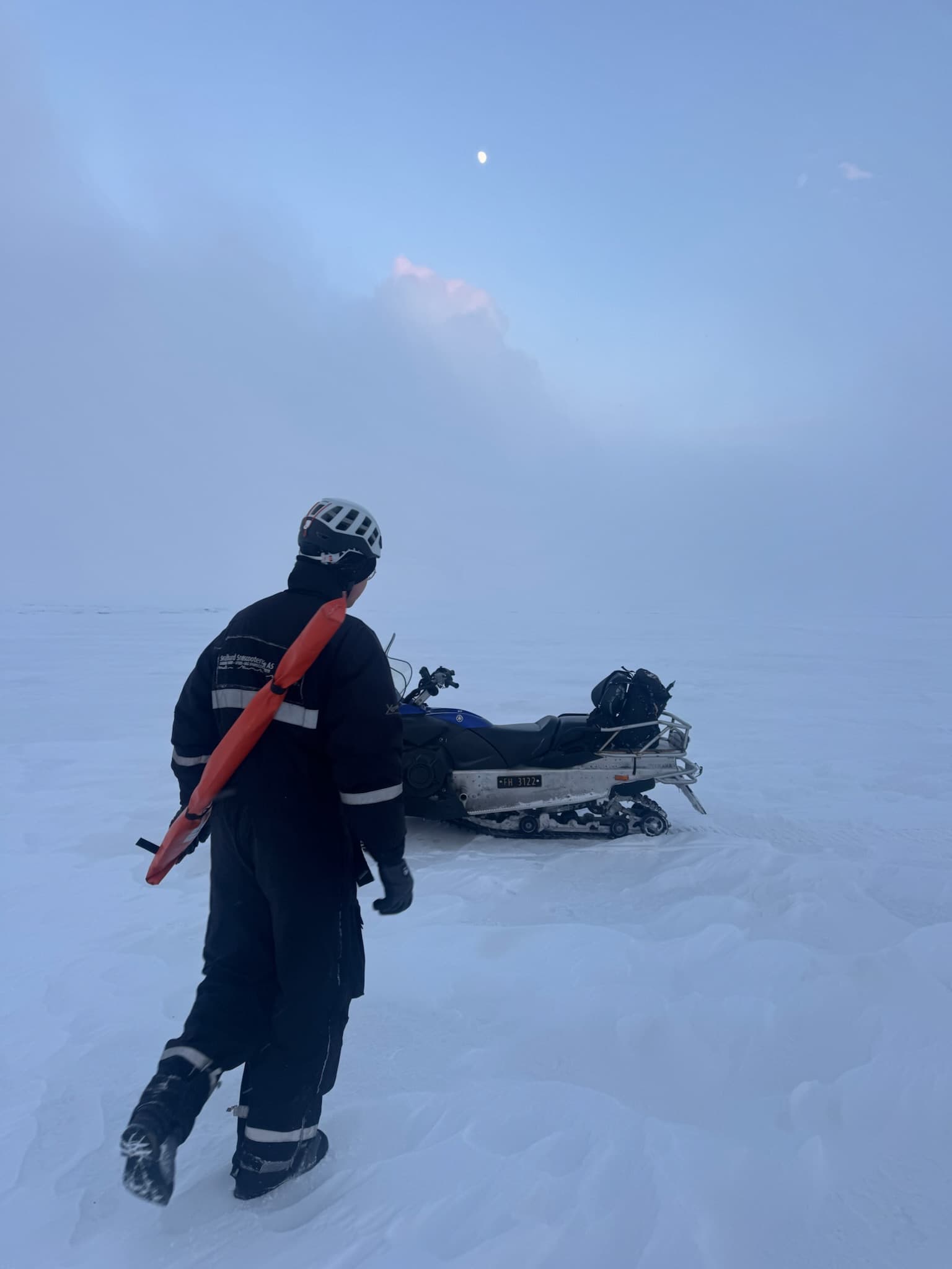 Guide mit Gewehr über der Schulter vor einem Schneemobil im Nebel auf Spitzbergen