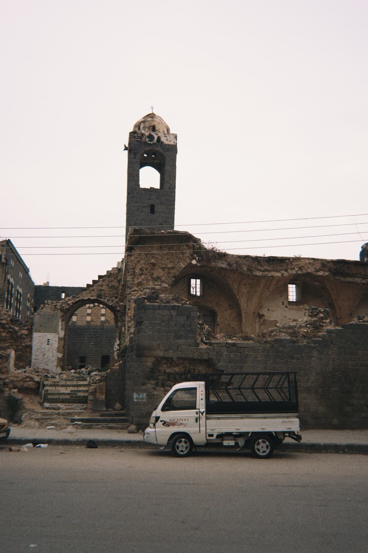 Burnt-out mosque with its minaret still standing, a white pickup parked in front